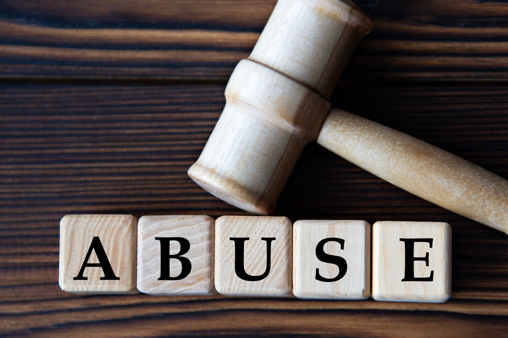 Wooden gavel resting on blocks spelling the word abuse, symbolizing legal action.