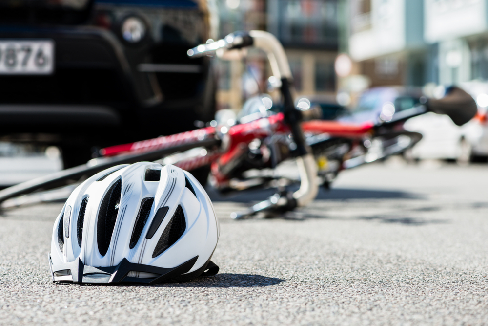 Bicycle accident scene with helmet on the ground after collision with a car.
