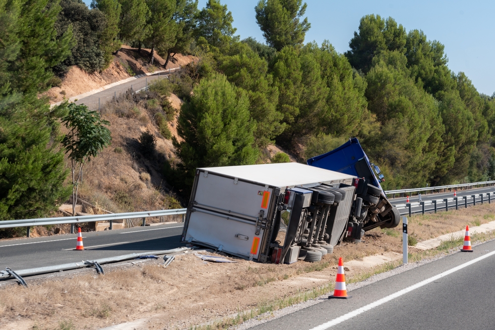 Overturned semi-truck on the side of a highway after an accident.