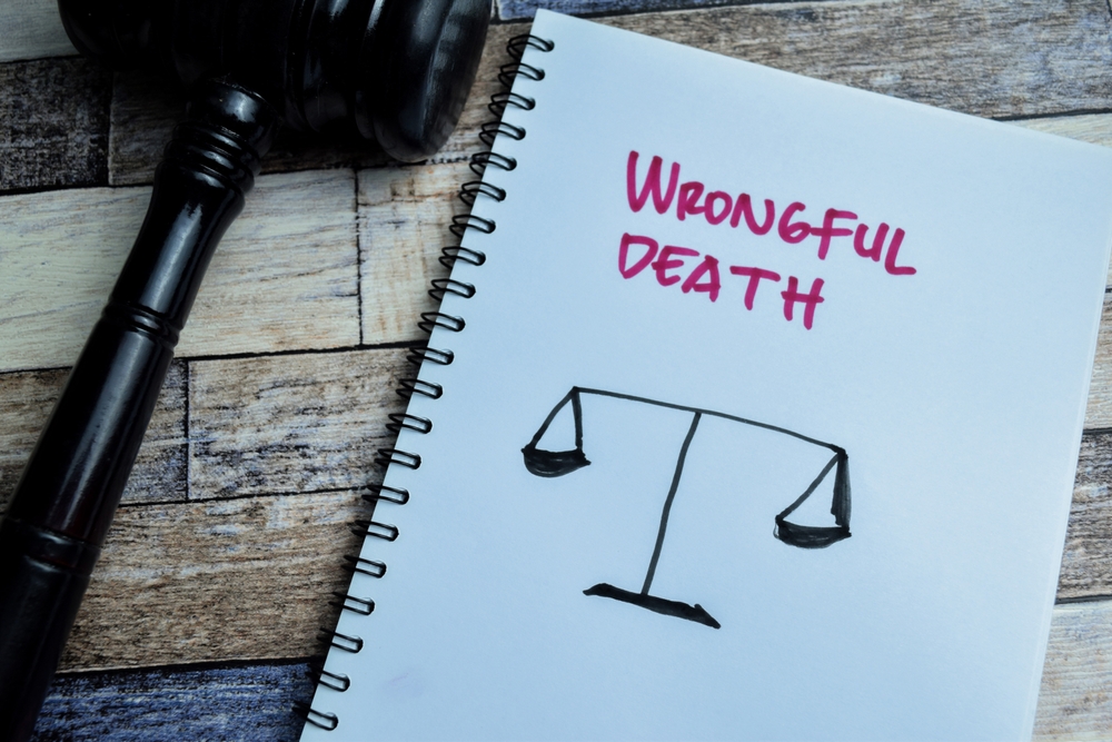 Notebook with the words Wrongful Death and a drawing of justice scales beside a gavel.
