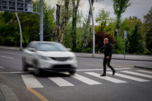 Car approaching a pedestrian in a crosswalk, illustrating a potential pedestrian accident